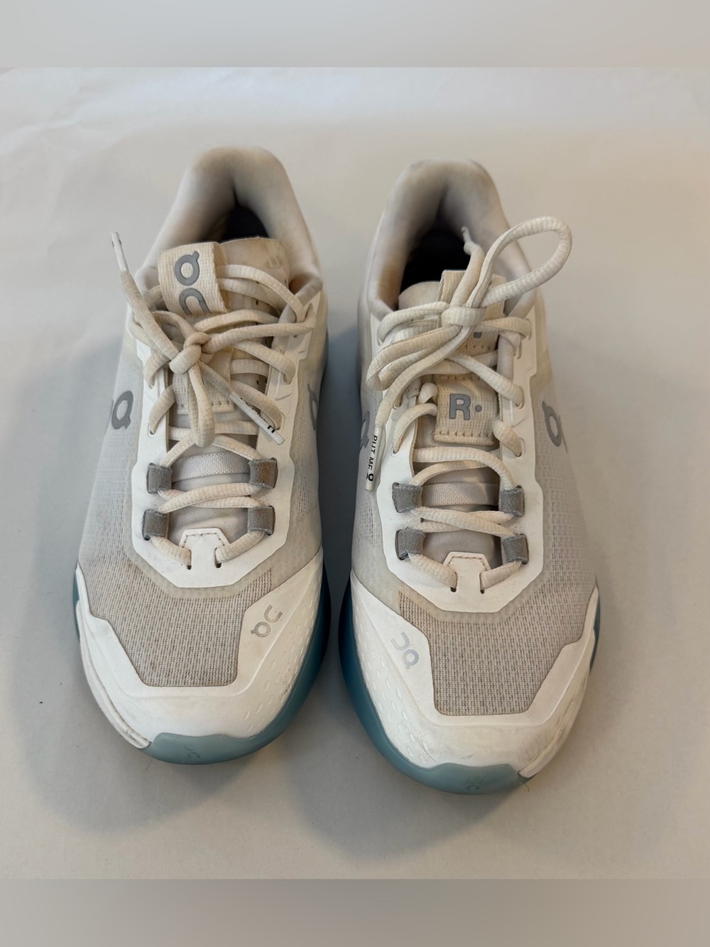 On Running/On Court Sneakers in off-white with Teal Accents.